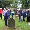 The Currie History Society peruse details on a headstone in Currie kirkyard